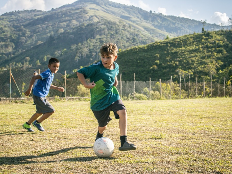 Niño jugando fútbol en cancha rural de Yolombó